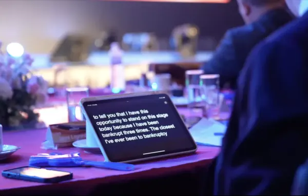 A tablet on a VIP table showing live Chinese-to-English captions
